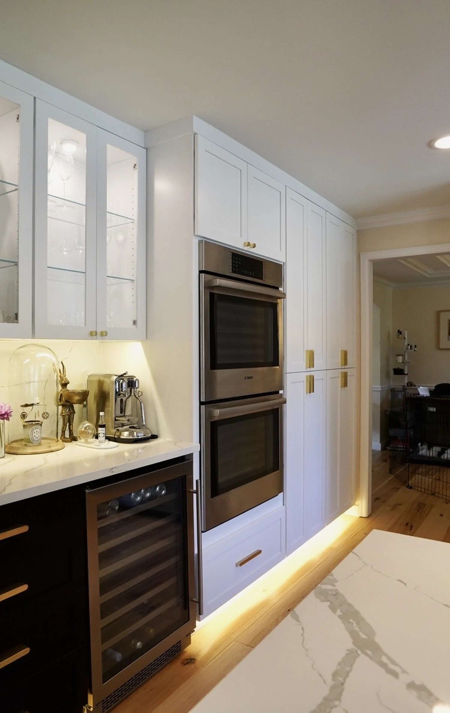 Kitchen with glass upper cabinets, marble surfaces and a built-in wine fridge.